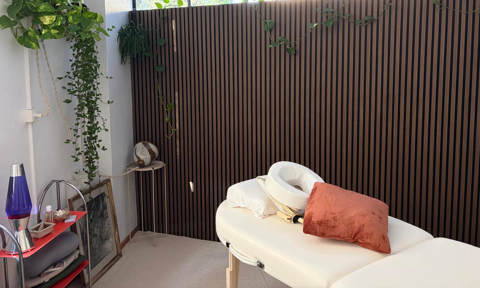 L'ambiance de l'Atelier du Corps à Territet : table de massage, mur en bois et plantes suspendues